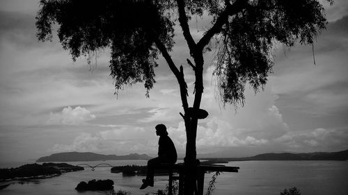 Rear view of woman standing by sea against sky during sunset