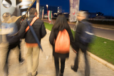 Rear view of people walking on street in city