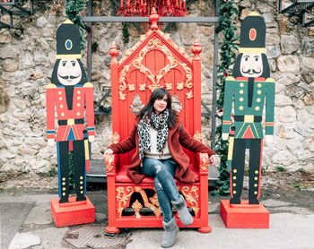 Portrait of woman sitting on red chair amidst decoration