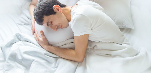 High angle view of man touching belly of pregnant woman while lying in bed