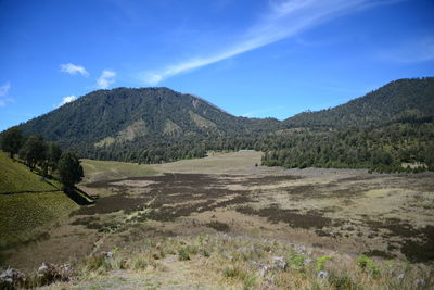 Scenic view of landscape and mountains against blue sky