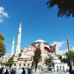 People in front of mosque against sky