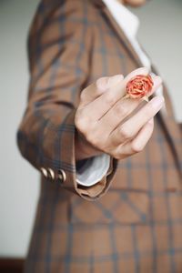 Midsection of businesswoman in suit holding flower