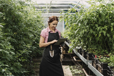 Female gardener using digital tablet in greenhouse