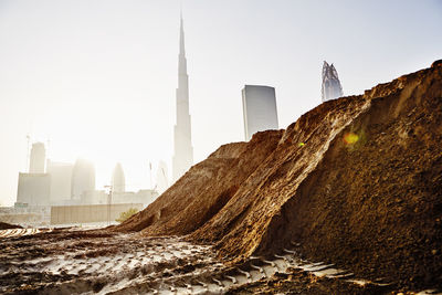 Pile of dirt at building site, dubai skyscraper on background