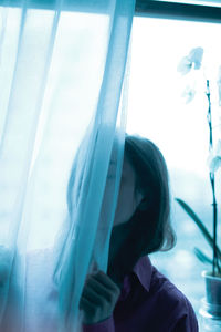 Portrait of woman looking through window