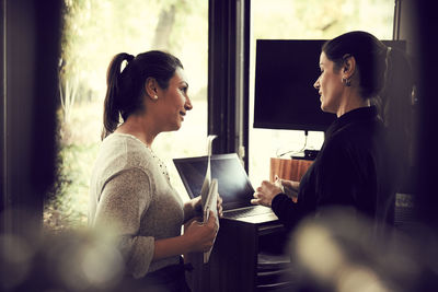 Female owner talking to customer about order while standing in cafe