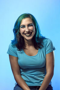 Portrait of a smiling young woman against blue background