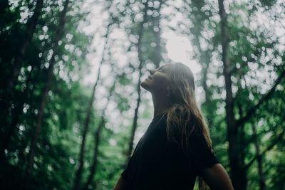 Low section of woman standing by tree in forest