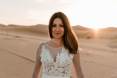 Close-up of a young brunette in her wedding dress in the middle of the desert as the sun rises 