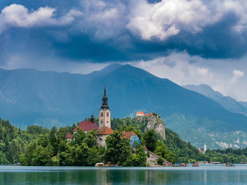 Church by lake against cloudy sky