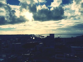 Cityscape against cloudy sky at sunset