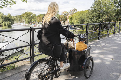 Mother riding bicycle with children in carriage