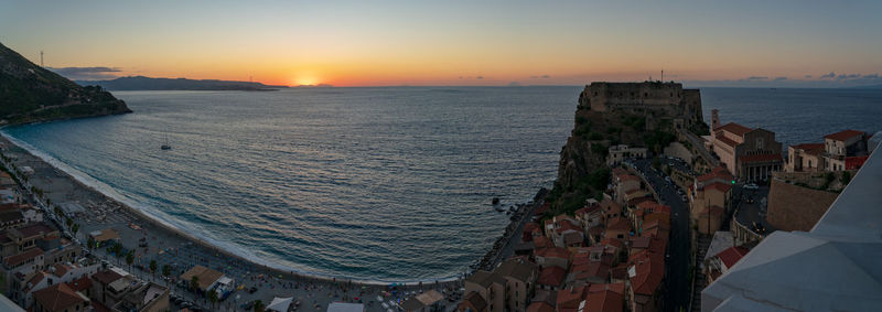 High angle view of sea and buildings against sky during sunset