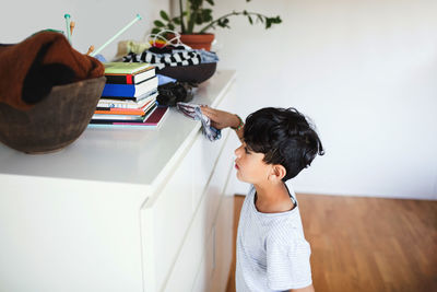 High angle view of boy cleaning cabinet with napkin at home