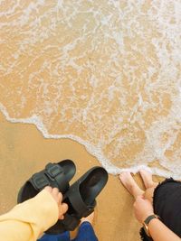 Low section of man holding hands on sand at beach