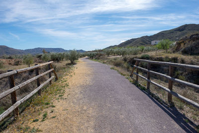 Empty road leading towards mountains against sky