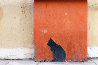 Shadow of red wall on footpath