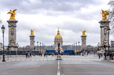 Group of people in city against cloudy sky