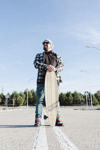 Portrait of a modern man holding the longboard.