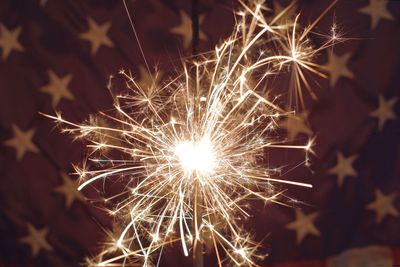 Close-up of sparkler against flag