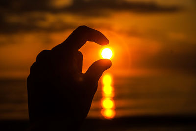 Silhouette hand against sky during sunset