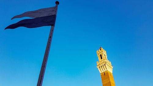 Low angle view of flags against clear blue sky