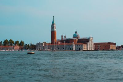 Cathedral by canal against clear sky