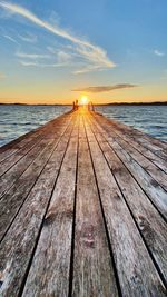 Pier over sea against sky during sunset