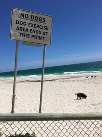 Information sign on beach against clear sky