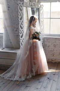 Close-up of woman standing on wall by window