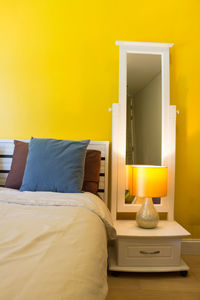 Electric lamp on bed against wall at home