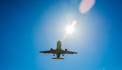 Low angle view of airplane flying against clear blue sky