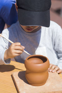 High angle view of boy painting pot on table