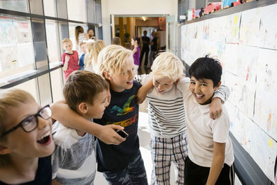 Tilt shot of cheerful friends in school corridor