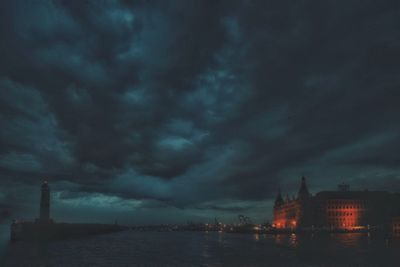 View of buildings against cloudy sky at night