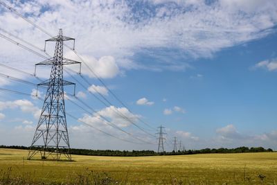 Low angle view of electricity pylon on field against sky