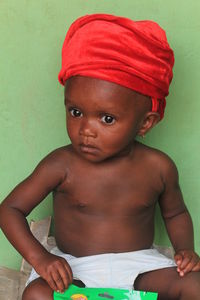 High angle view of shirtless boy sitting on bed at home