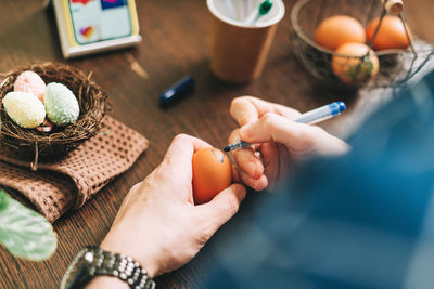 Easter day. adult man painting eggs on wooden background. sitting in a kitchen. preparing