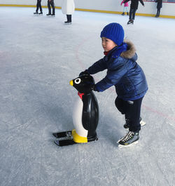 Boy learning ice skating with penguin