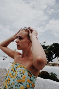 Young woman wearing eyeglasses against sky