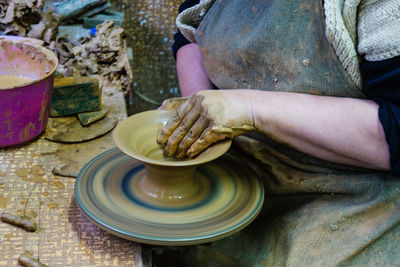 Midsection of craftsperson making container at workshop