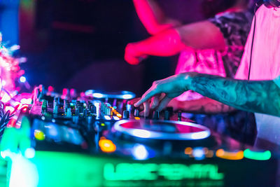 Cropped hand of man with illuminated audio equipment at night