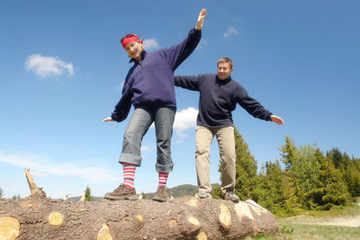 Young couple balancing on cut wooden log