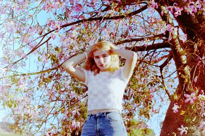 Portrait of young woman standing on tree