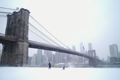 People walking on suspension bridge in city
