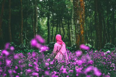 Rear view of woman with pink flowers in forest