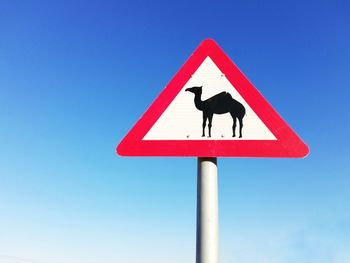 Road sign against clear blue sky