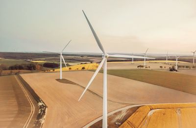 Wind turbines on field against sky