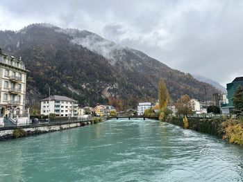 Buildings by river against sky